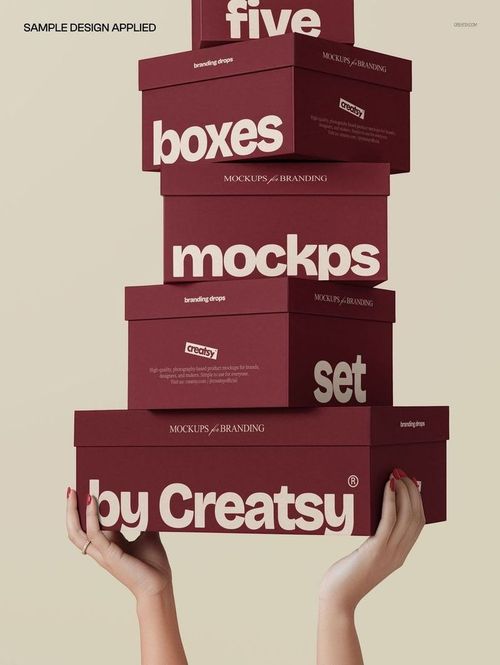 Stack of maroon rectangular boxes with bold white text, held by two hands against a beige background, packaging mockup.