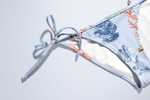 Detailed close-up of a bikini mockup showing blue and orange coral motifs, white lining, and knotted side ties.