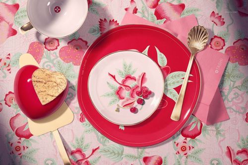 Top view of a Valentine-themed cake plate mockup with red and white floral designs, gold utensils, and heart-shaped dessert.