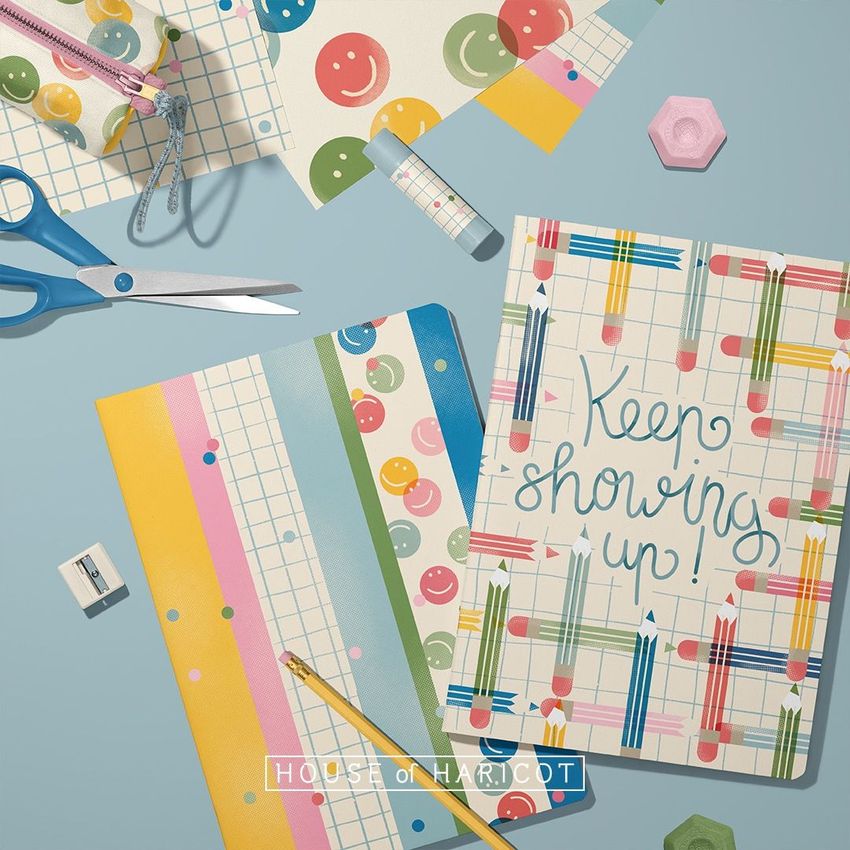 Stationery mockup featuring two classic A4 notebooks with colorful geometric and smiley face patterns on a blue surface.