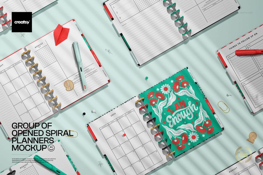 Flat lay of spiral planners mockup with open pages, decorative covers, pens, and paper clips on a mint background.