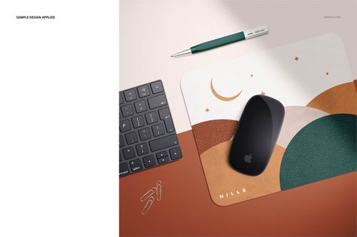 Angled top view of a rectangular mouse pad mockup with curved shapes and earthy tones, placed beside a keyboard, pen, and paper clips.