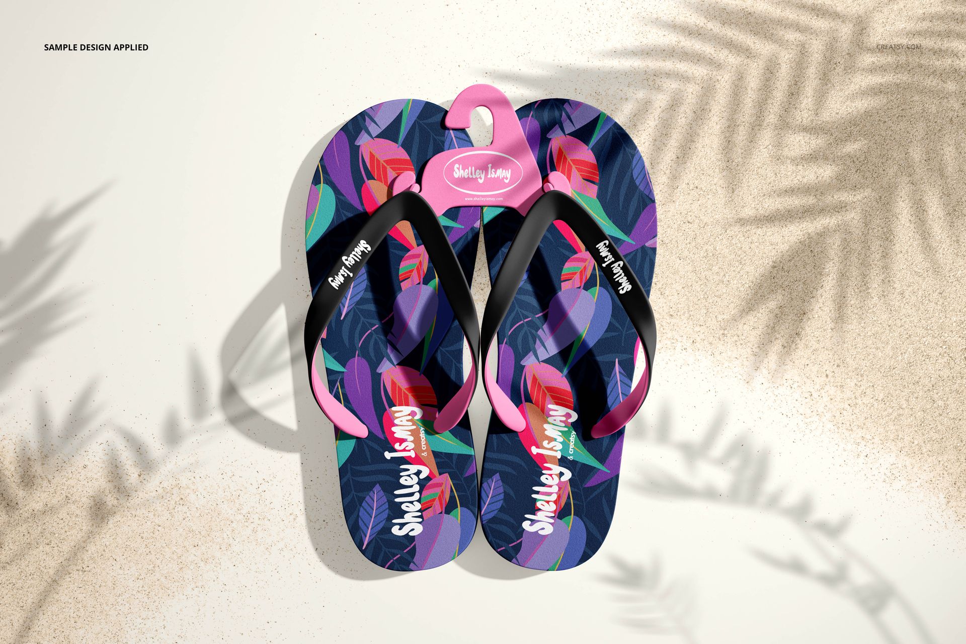 Flip flops mockup displaying bold multicolored botanical artwork, arranged side by side on a light sandy setting.