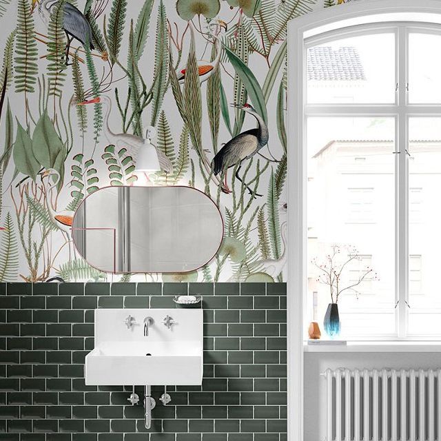 Vintage bathroom mockup featuring a botanical wallpaper with birds above green tile, a white sink, and a large window.