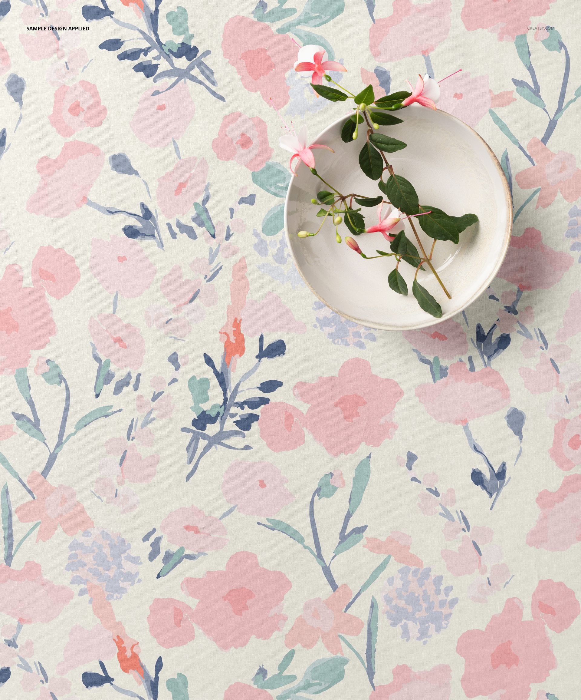 Cotton fabric mockup shown from above, decorated with soft pink and blue floral designs and a bowl with flowers.