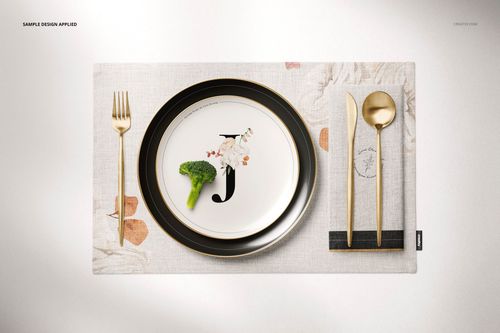 Top view of a placemat mockup featuring a plate with food, gold cutlery, and a napkin on a light patterned surface.