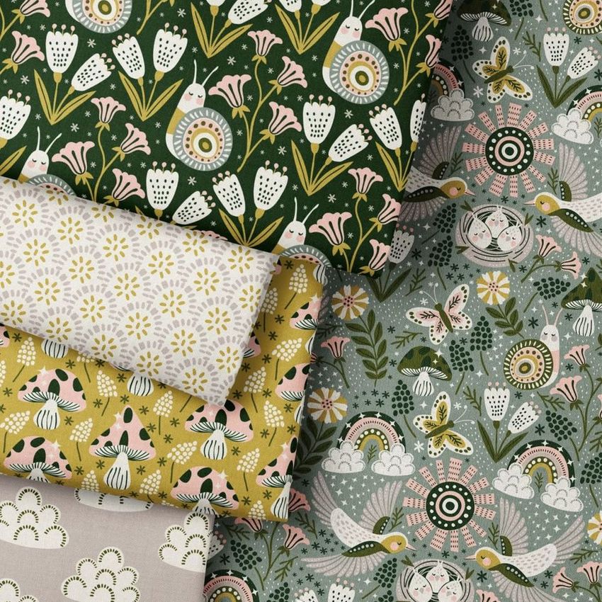 Folded fabrics mockup displaying five pieces with various floral, animal, and geometric patterns in green, yellow, and pastel tones.
