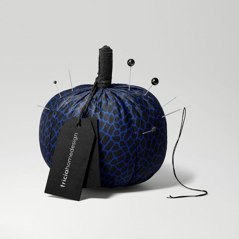 Fabric pumpkin mockup featuring a blue and black animal print design, used as a pincushion with pins and a black tag attached.