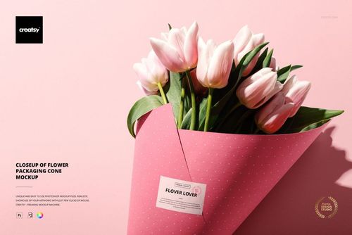 PSD mockup showing a bouquet cone with pale pink tulips, wrapped in dotted pink paper, on a soft pink studio surface.
