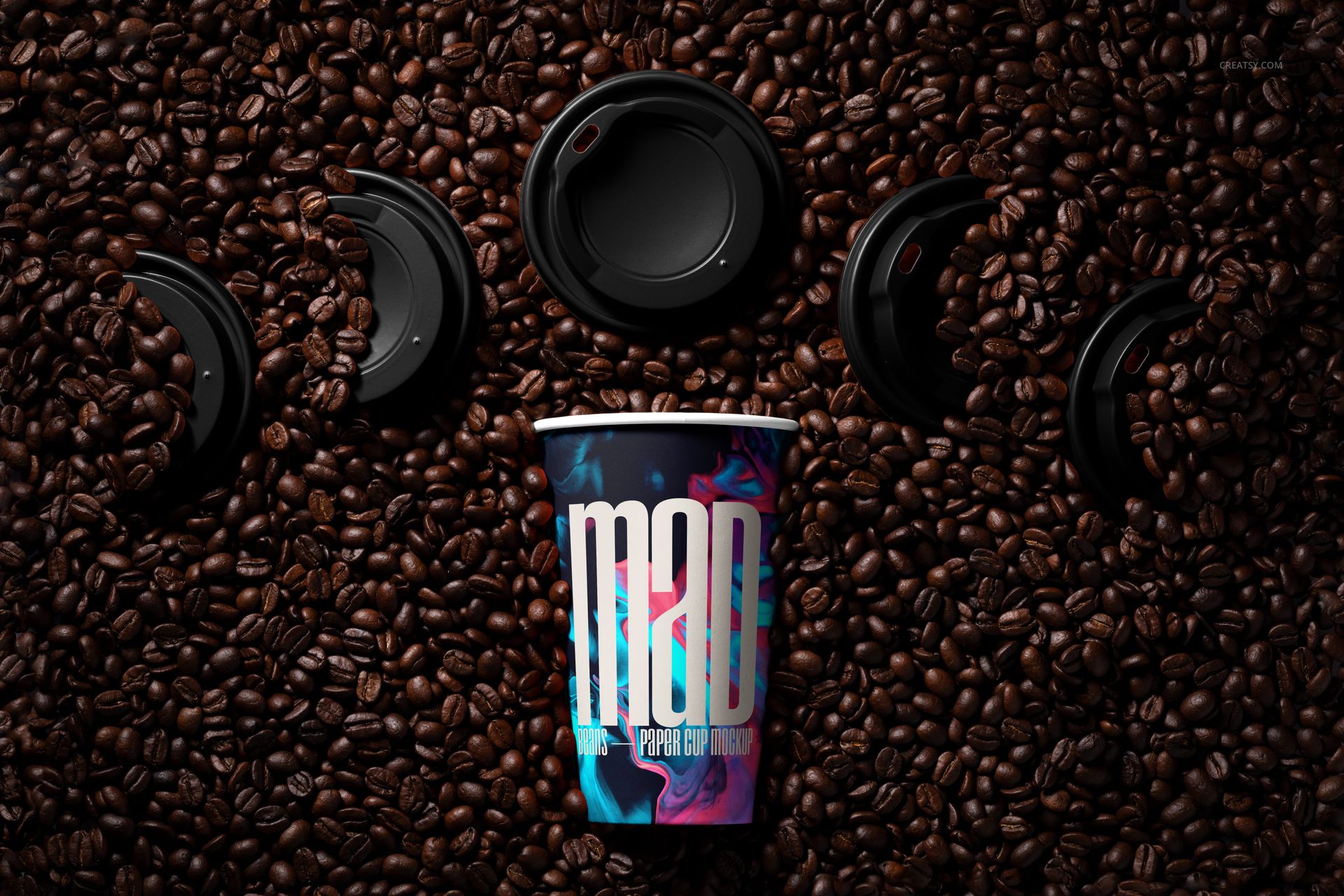 PSD mockup showing a paper cup with a bold graphic design, set in a bed of coffee beans with loose lids nearby.