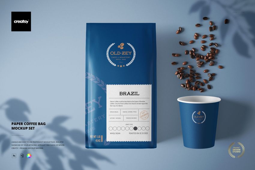 Front view of a blue paper coffee bag and matching paper cup with coffee beans scattered on a light surface, PSD mockup scene.