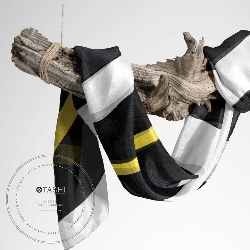 Habotai silk scarf mockup draped over a piece of driftwood, featuring large black, white, and yellow stripes on a light background.