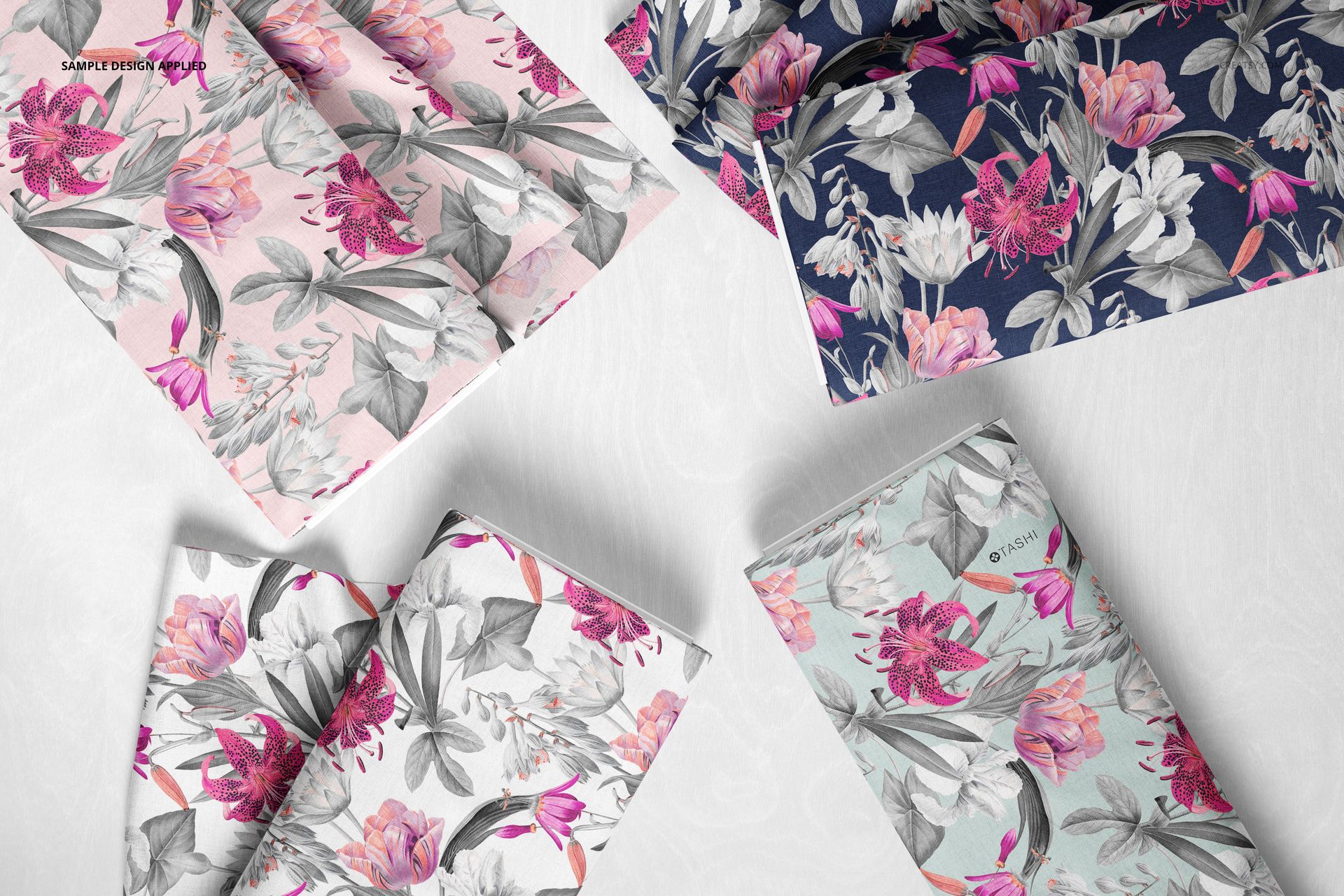 PSD mockup showing fabric bolts in floral prints, with pink, gray, and navy colors, arranged on a neutral surface.