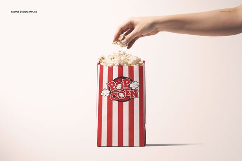 Popcorn paper bag mockup with vertical red and white stripes, overflowing with popcorn, hand grabbing popcorn.