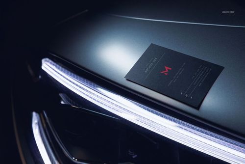 Automotive-themed business card mockup placed on a metallic car surface with bright LED light accents.
