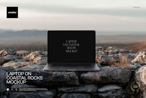 Front-facing laptop sitting atop textured coastal rocks outdoors, featuring a PSD mockup screen.