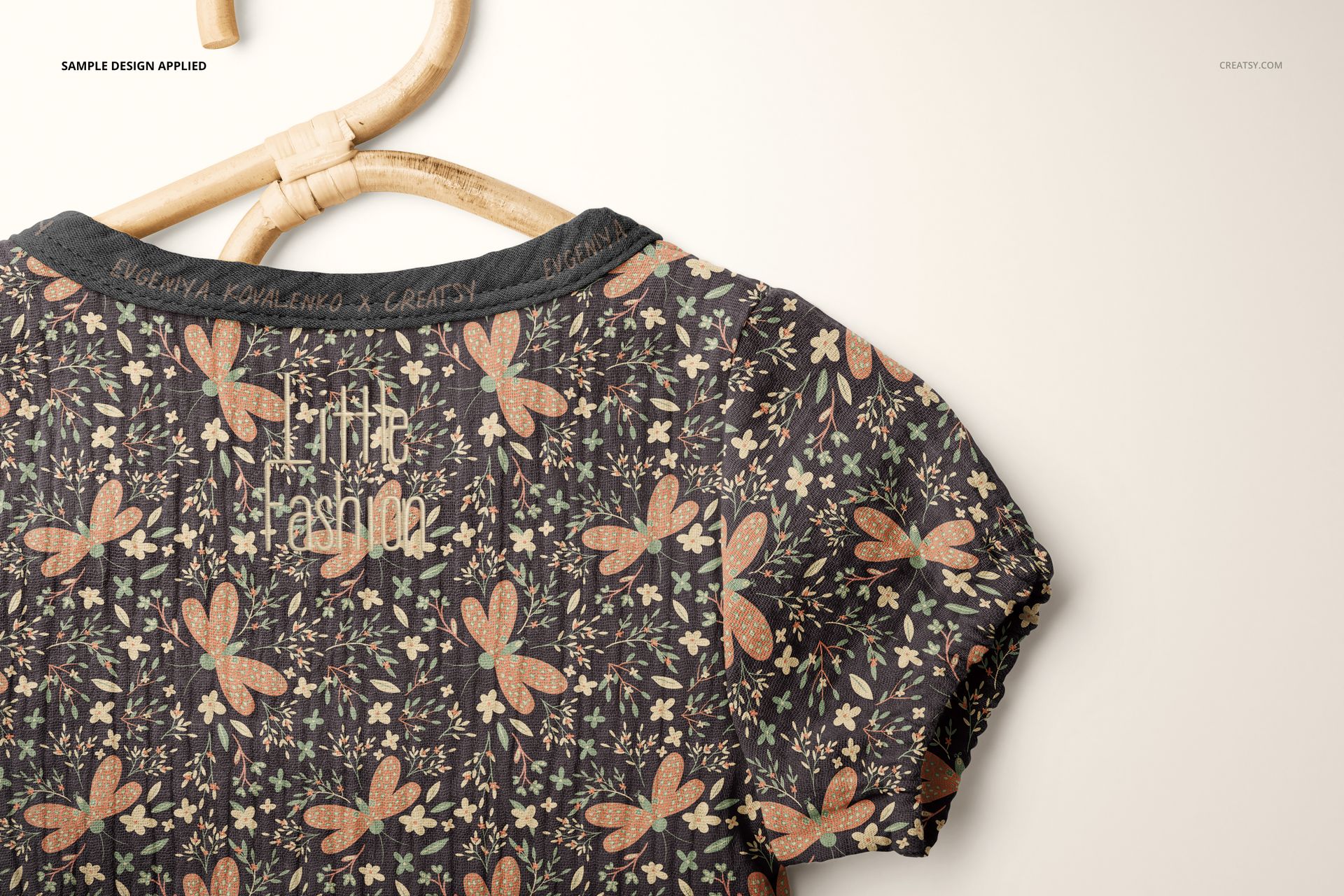 Short-sleeve muslin onesie mockup with a floral pattern in earthy tones, displayed on a wooden hanger, top view.
