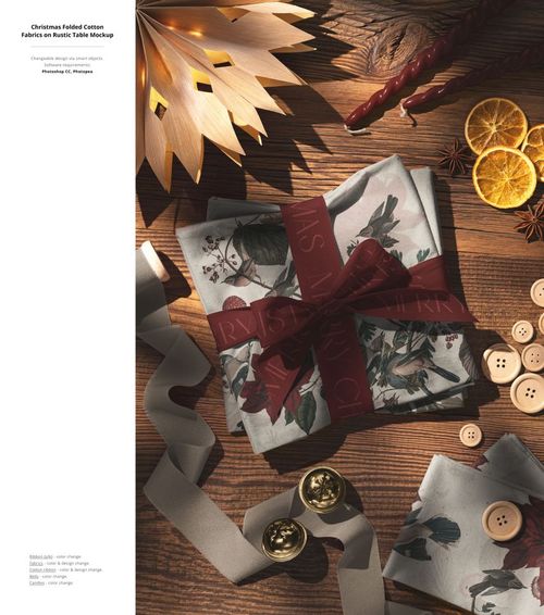 Christmas gift wrapped in floral fabric with a red ribbon on a rustic wooden table, surrounded by holiday decorations.