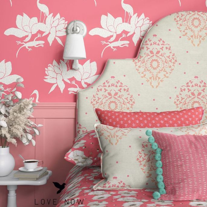 Bedroom mockup showing a bed with a patterned headboard, decorative pillows, and coral wallpaper with floral motifs.