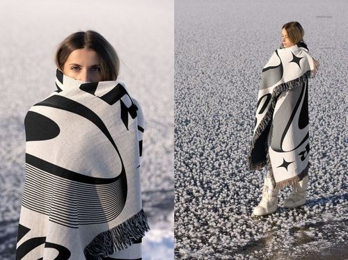 Black and white patterned jacquard blanket mockup draped over a person standing on a snowy ground, winter scene.