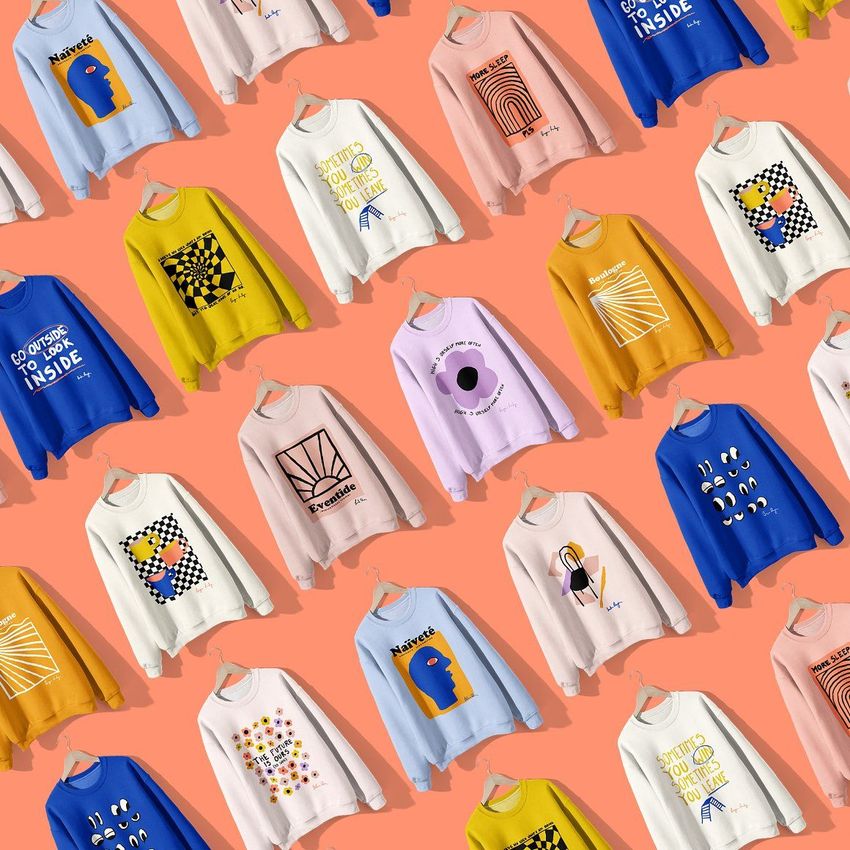 Sweatshirt mockup set showing multiple sweatshirts with colorful naive art designs, arranged diagonally on a peach background.