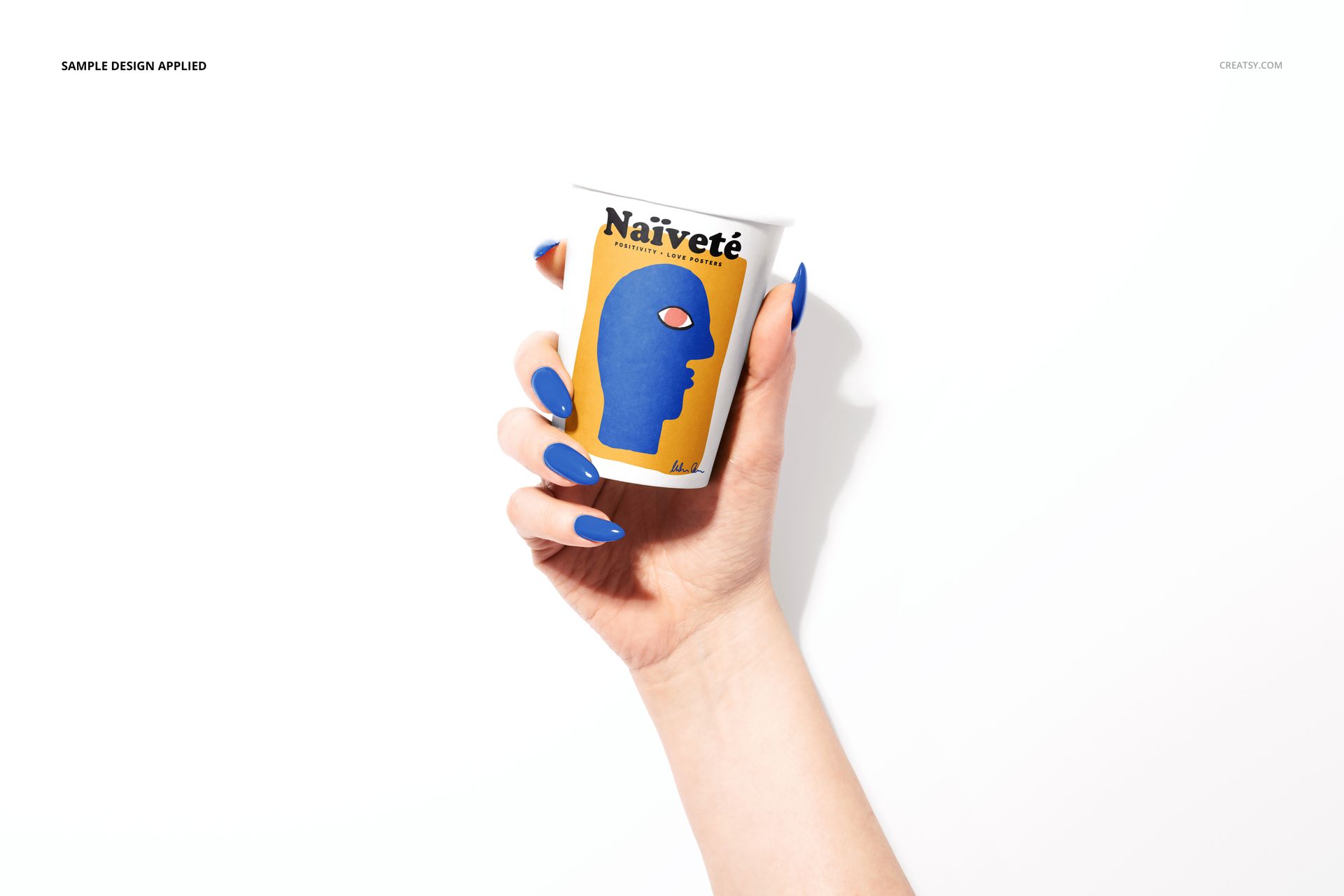 PSD mockup showing a paper cup in a female hand, decorated with a colorful face illustration and white backdrop.