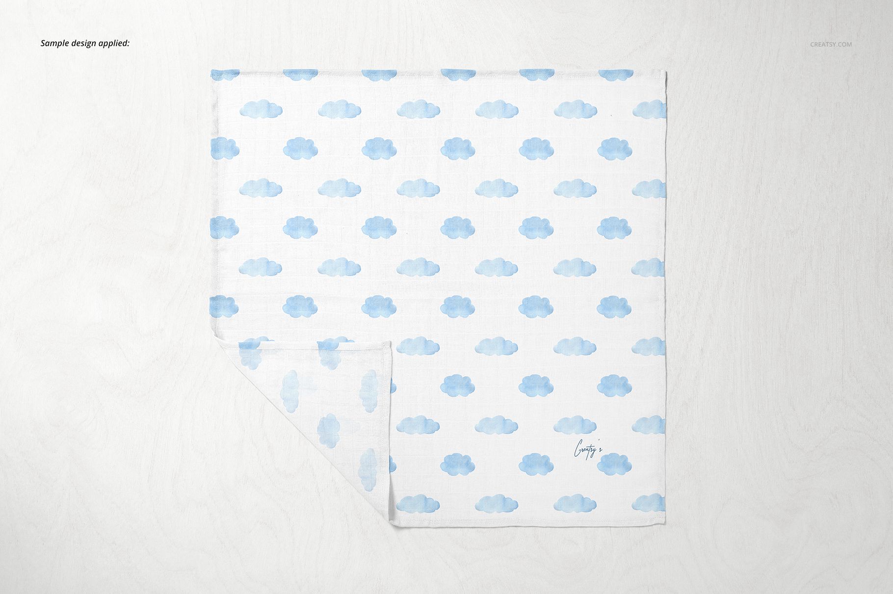 Baby muslin square nappy with blue cloud pattern, shown flat on a light surface in a top view mockup.