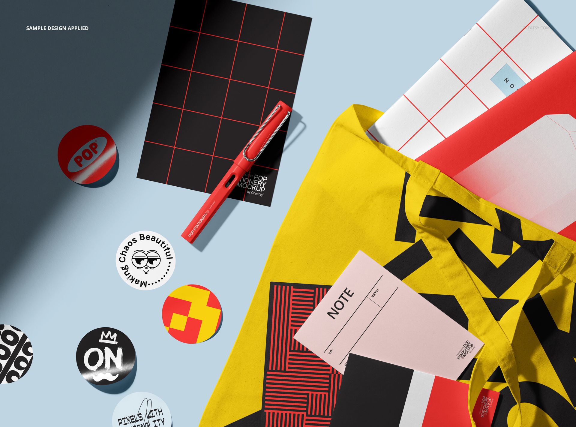 PSD mockup showing a tote bag with graphic design and various stationery pieces, viewed from above on a blue background.