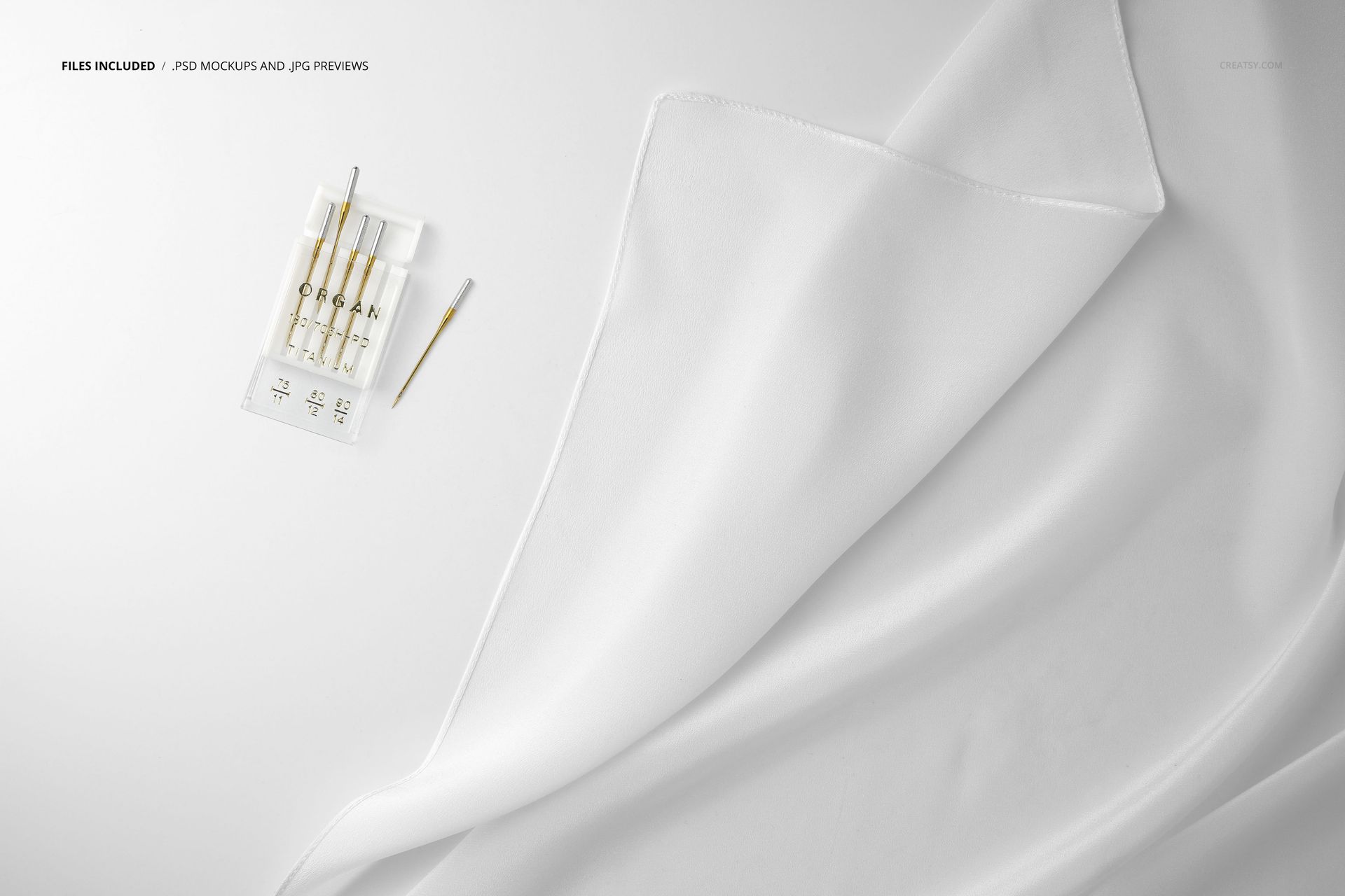 Close-up view of a white silk scarf mockup draped on a flat surface with sewing needles placed nearby.