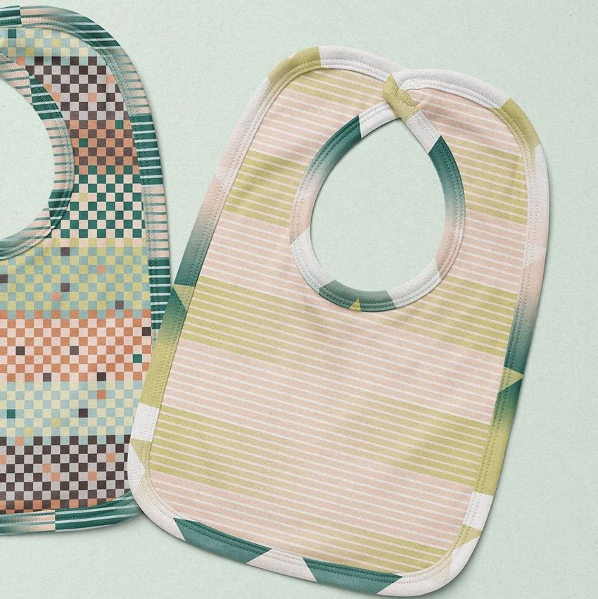 Two velcro fastening baby bibs mockup displayed on a light surface, featuring pastel geometric and striped patterns.