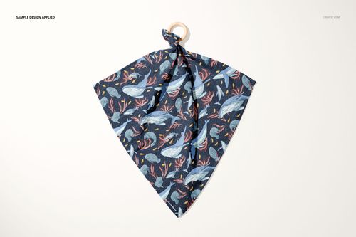 Top view of a muslin cloth wooden teether mockup, dark blue fabric with whale and sea life illustrations, ring attached.