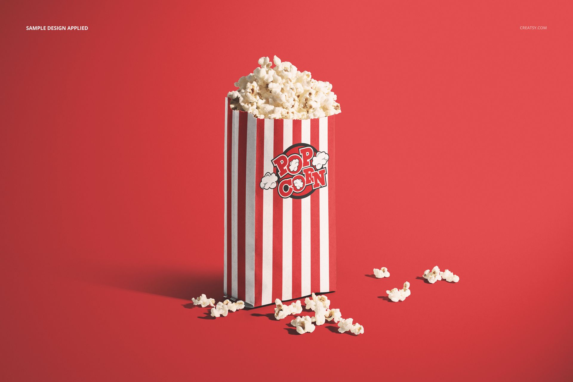 Popcorn paper bag mockup featuring a striped design in red and white, filled with popcorn, on a red surface.