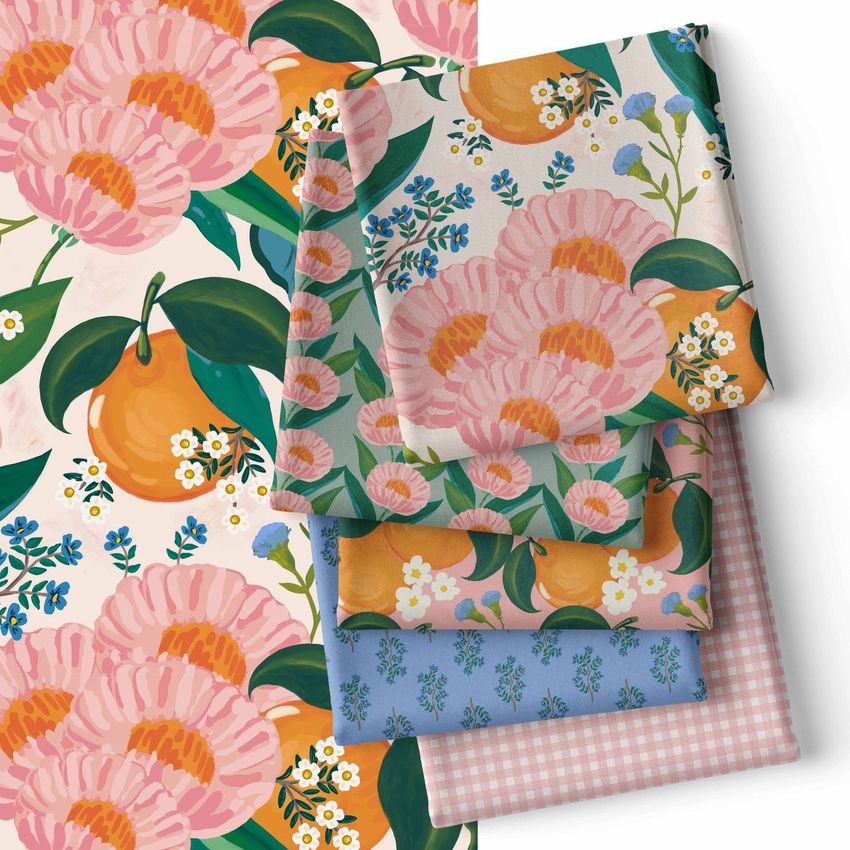 Folded fabrics mockup showing four stacked fabric pieces with floral and fruit patterns in pink, orange, blue, and green tones.