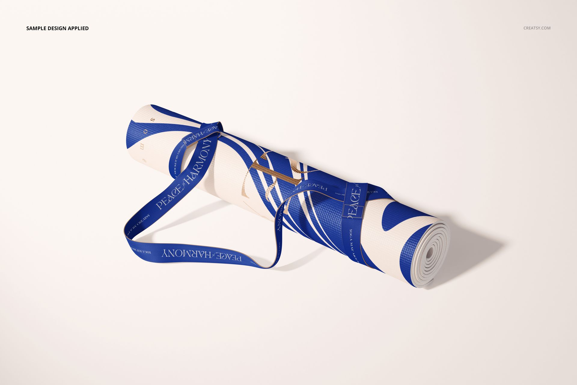 Yoga mat mockup featuring a rolled mat with blue and white design, blue strap, and shadow, displayed on a pale background.