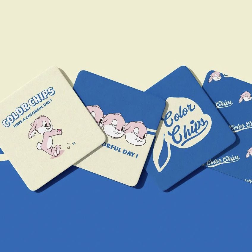 Square coasters mockup featuring five coasters with playful bunny illustrations and text, arranged on a blue and cream surface.
