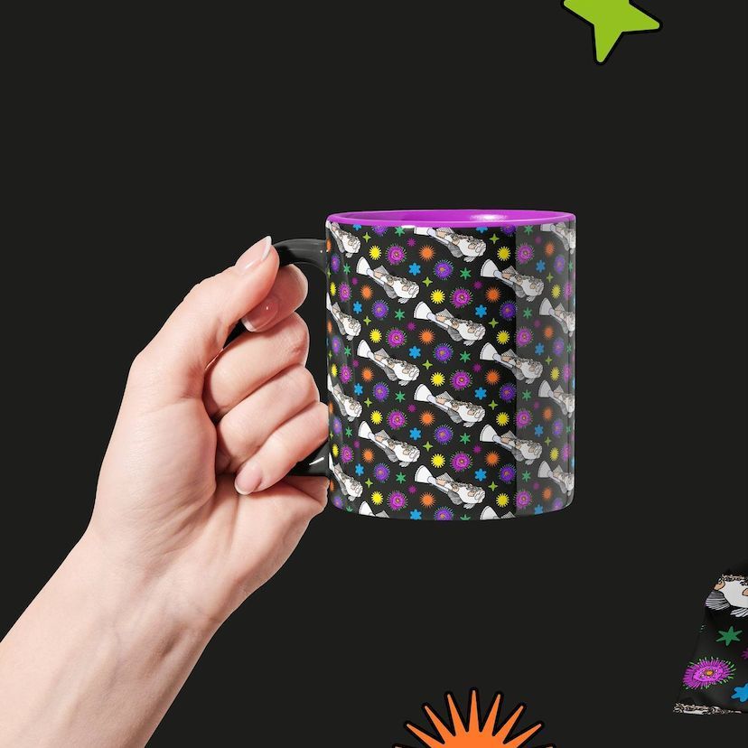 Hand holding a custom mug mockup with a repeating pattern of white cats and colorful stars on a black background, purple interior visible.