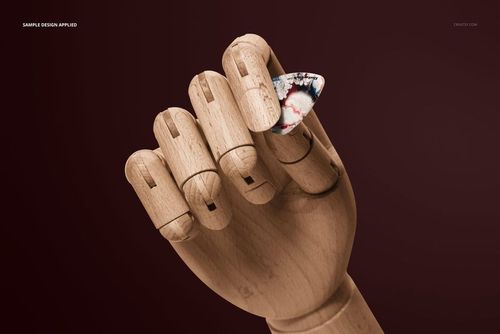 Close-up of a wooden hand model gripping a colorful guitar pick, set on a solid dark red backdrop, PSD mockup.