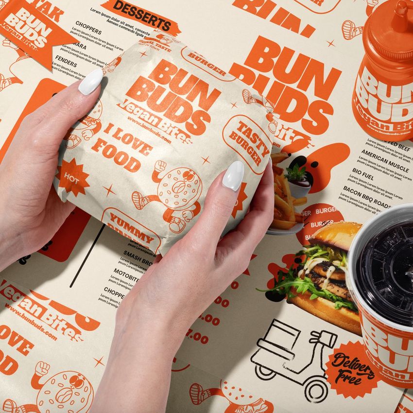 Vegan burger bar packaging mockup featuring branded wrap, menu sheet, takeaway drink, and playful orange graphics.