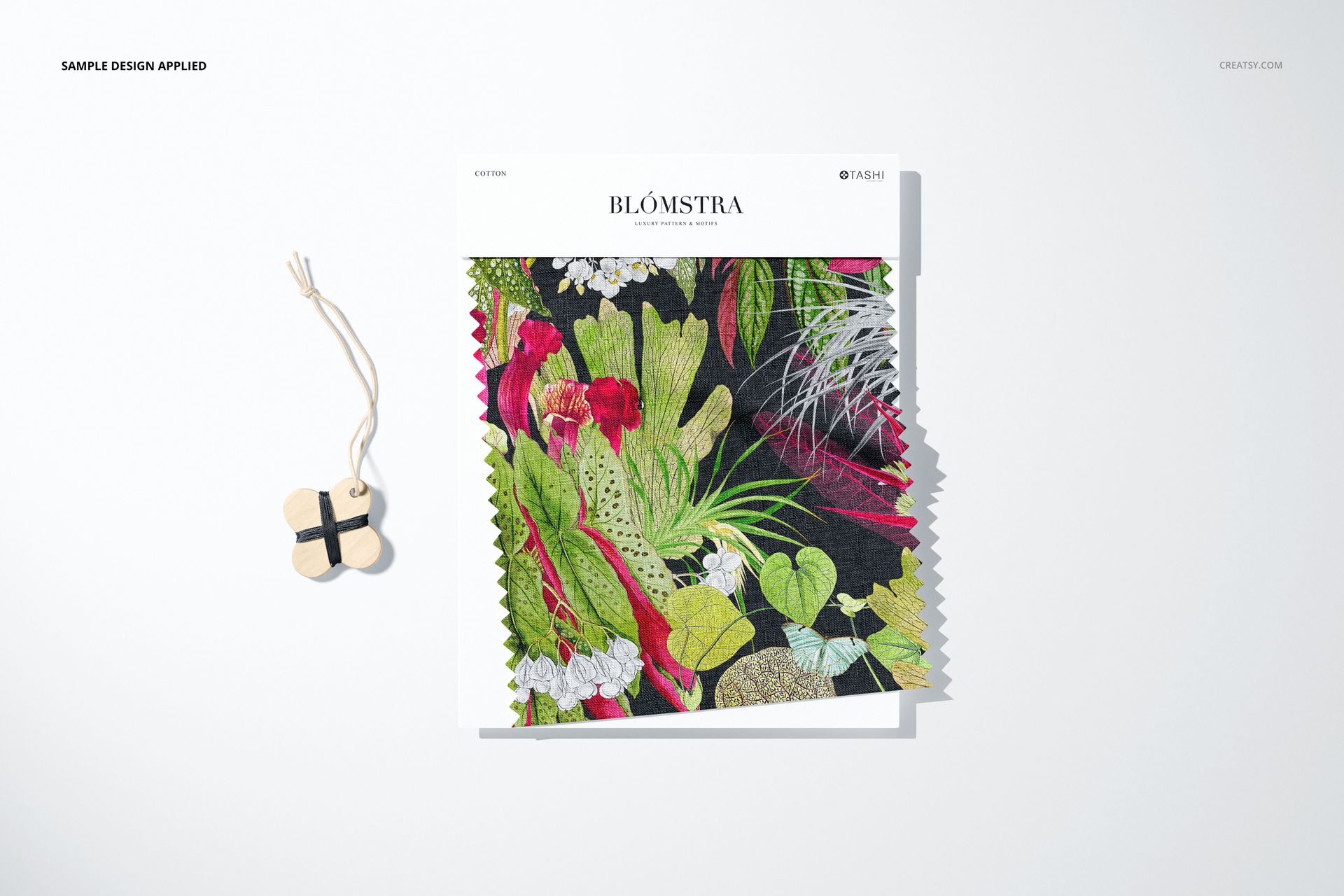 Fabric swatch mockup featuring vibrant floral and leaf designs, shown with a zigzag edge and a wooden thread winder prop.