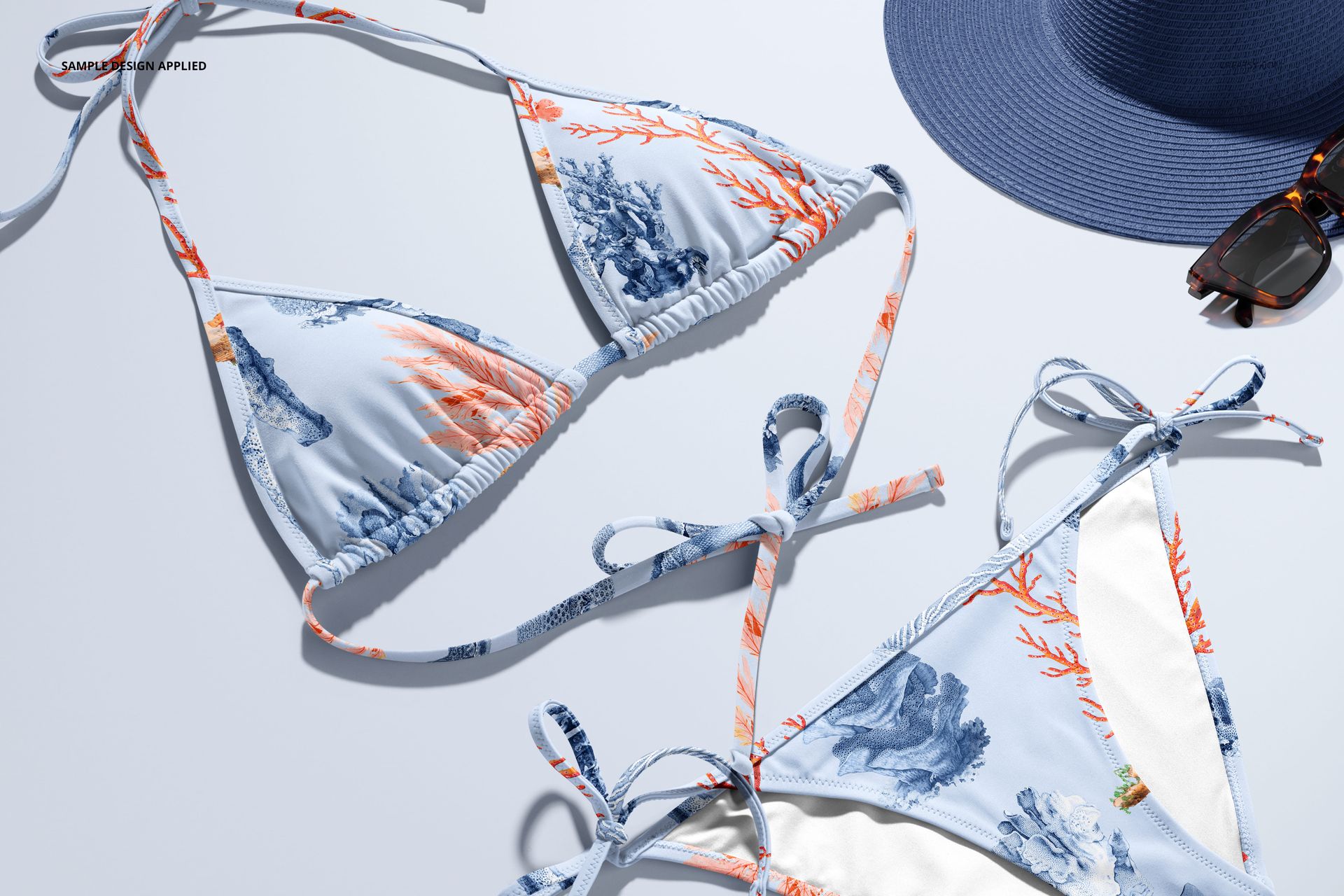 Front view of a bikini mockup set with blue and orange coral reef patterns, displayed on a light surface.