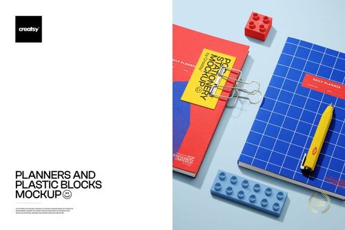 Stationery mockup featuring planners, colorful plastic blocks, a pen, and binder clips displayed from above on a blue tabletop.