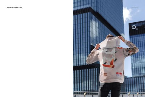 PSD mockup of an oversized hoodie with large hood and multicolored patterns, displayed outside by modern architecture.