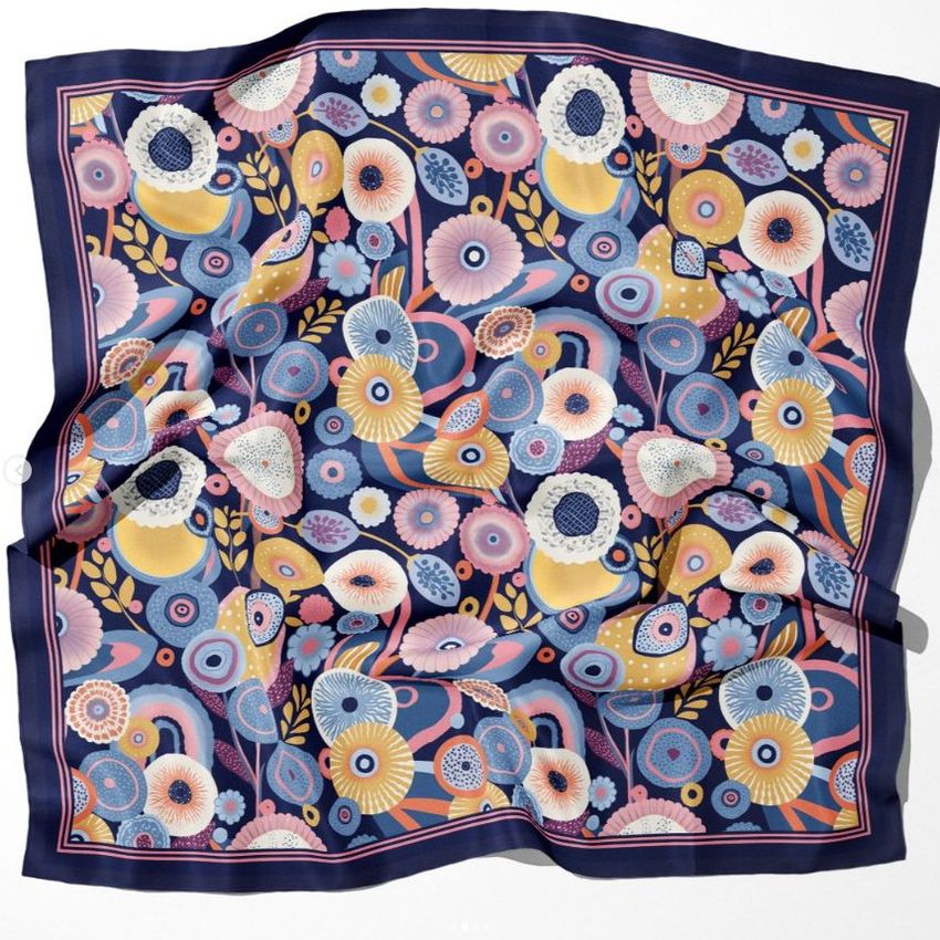 Silk scarf mockup featuring a colorful floral pattern with abstract flowers in blue, yellow, pink, and white on a dark background.