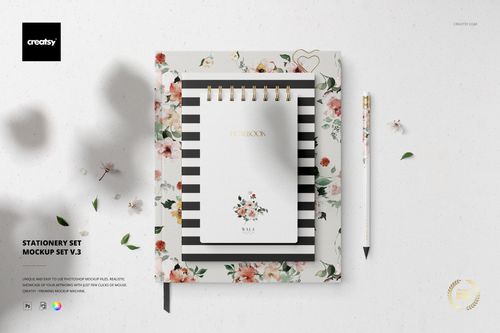 Top view of a stationery set mockup featuring a floral-patterned notebook, striped notepad, and pen on a light background.