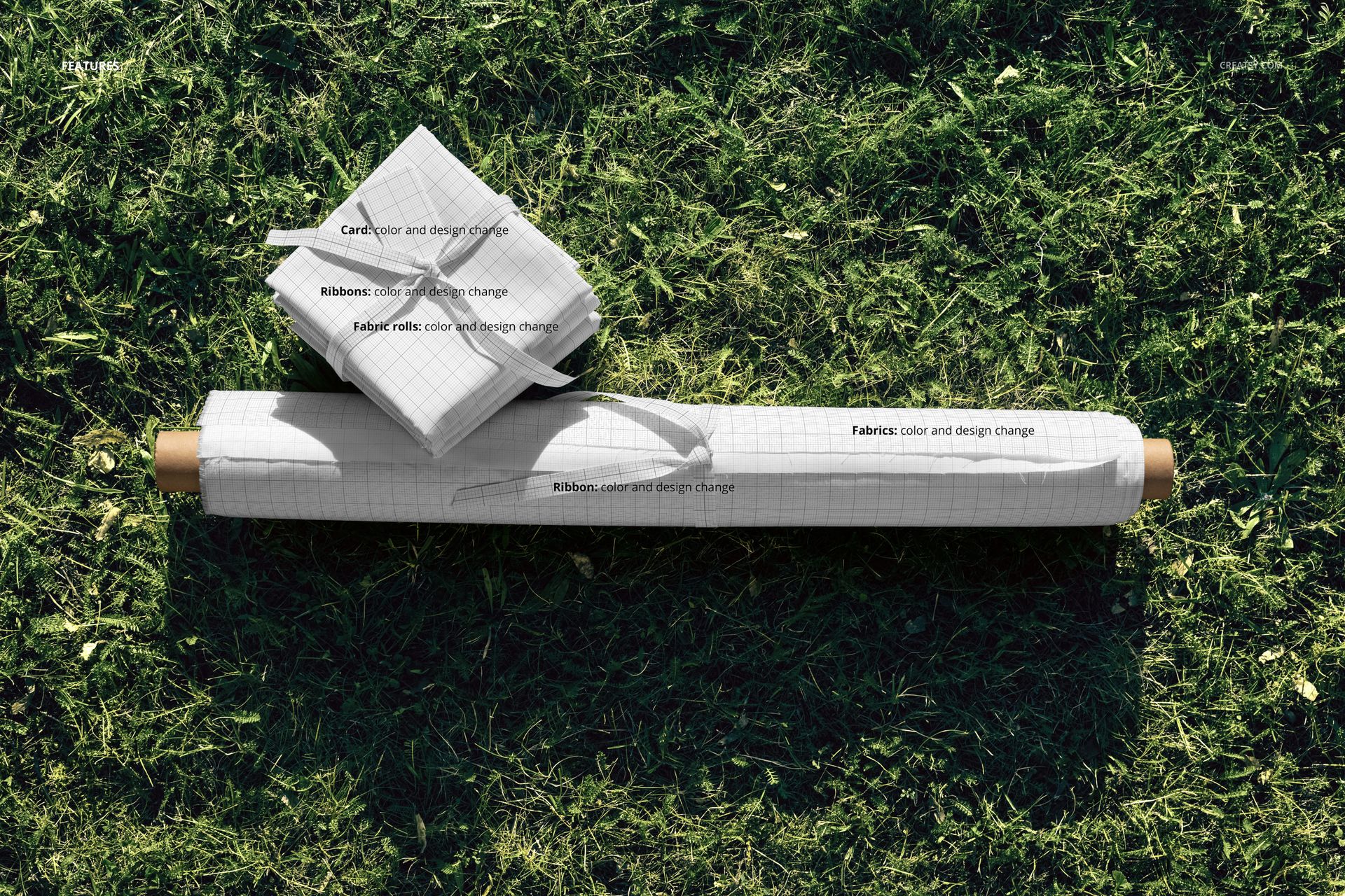 PSD mockup featuring a fabric roll and folded fabric squares with subtle grid design, placed outdoors on grass.