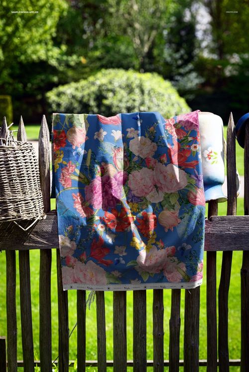 PSD mockup showing a decorative fabric with a bold flower print hanging over a wooden fence in natural sunlight.