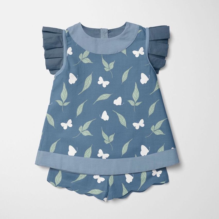 Kids blouse and shorts mockup featuring a blue outfit with white butterfly and green leaf pattern on a light background.