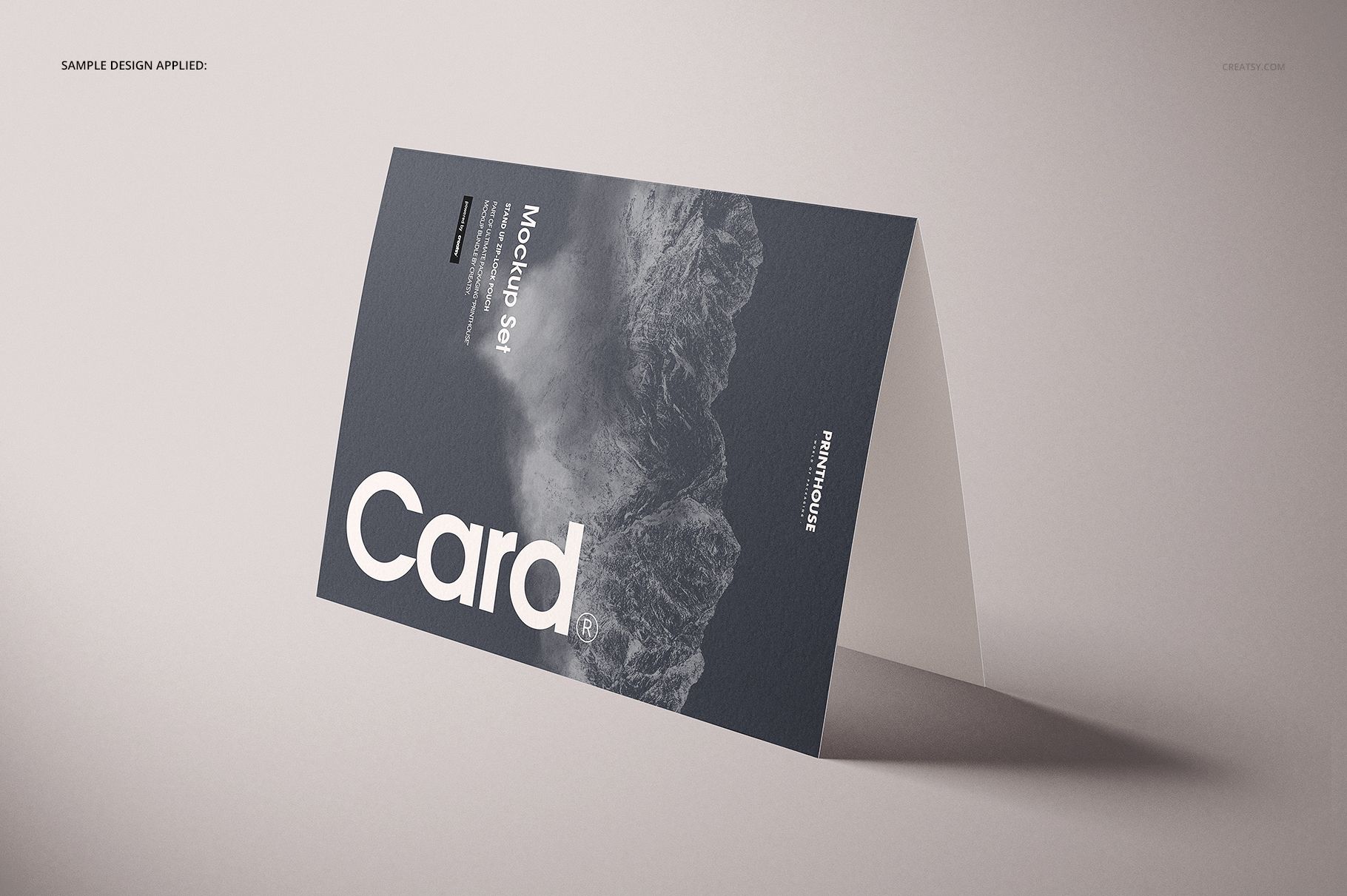 Angled front view of a folded A4 card mockup with a textured dark cover, white lettering, and landscape imagery.