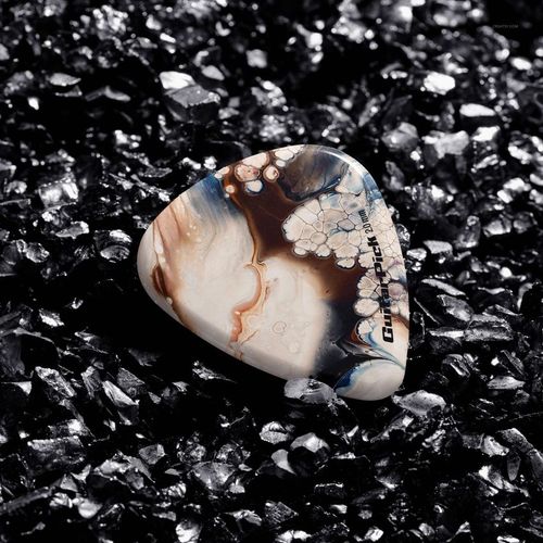 Marbled guitar pick placed on glossy black gravel, highlighting texture and detail in a high-resolution mockup scene.
