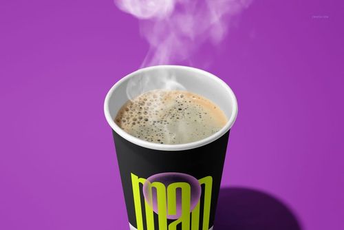 Paper cup mockup displaying coffee with foam and steam, black cup with yellow lettering, set on a purple surface.